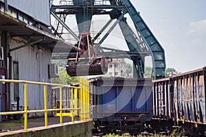 Crane loading train wagon with coal from barge