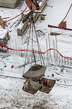 Crane lowers containers for concrete at a construction site