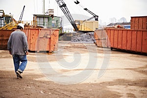 Crane, machine and engineer man in junkyard to recycle metal for sustainability, manufacturing or pollution. Vehicle