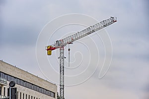 Crane near the brick high-rise building under construction against the blue sky, modern construction