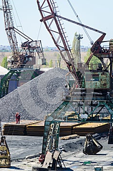 Crane in river port. Heavy cranes unloading metal to import. Steel delivery