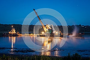 Crane on the ship produces sand on the river