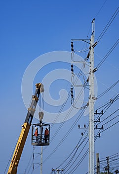 Crane truck lifting electricians in meta basket to working on electric power pole