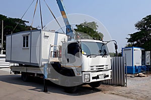 The Crane trucks transport the mobile office buildings or container site office for installation in the construction site area,