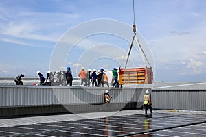 Crane Uploading Solar PV panels on Roof with Installation Workers