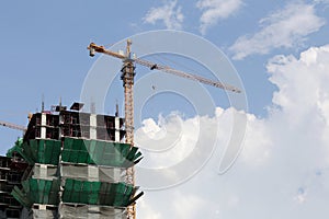 Crane working on a building under construction in day time.