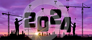 Cranes building construction 2024 year sign. Black silhouette staff works as a team to prepare to welcome the new year 2024. photo