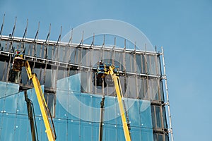 Cranes on glass facade office building under construction