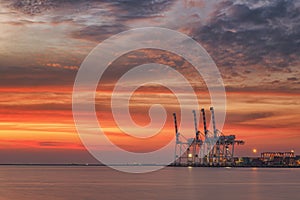 Cranes and industrial cargo ships in Varna port at sunset