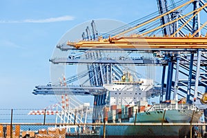 Cranes load containers on a large transport ship at trade port