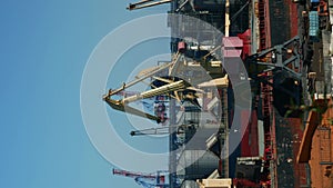 Cranes loading ships at sea port, timelapse. Vertical video. Logistic concept