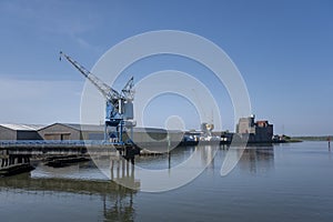 Cranes near the river against blue sky. Industrial landscape, industrial zone