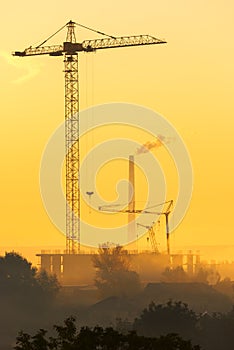 Cranes over new buildings in the early foggy morning.