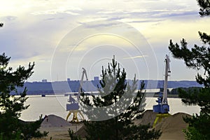Cranes for sand extraction on the bank of the Volga River in the middle of the forest