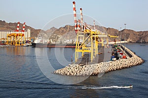 Cranes in shipping port near mountains