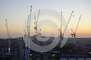 Cranes surrounded by buildings during the sunset in the evening in Edinburgh in Scotland