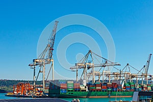 Cranes unloading a ship in a harbor. Koper, Slovenia - 27.07.2019
