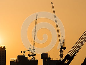 Cranes working at Building Construction site sunset sky Silhouette Industrial background