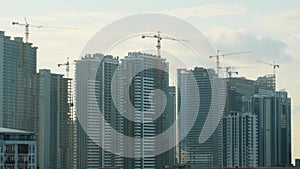 Cranes working on construction site of building modern city district with skyscrapers, multi storey houses, industrial