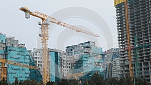 Cranes working on construction site of building modern city district with skyscrapers, multi storey houses, industrial