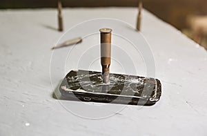 Crashed black smartphone with a bullet on white background. Broken lcd touch screen. Information technology photo. War concept