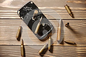 Crashed black smartphone with a bullet on white background. Broken lcd touch screen. Information technology photo. War concept