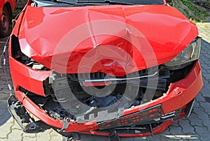 Crashed car of red color. Front view of the wrecked vehicle. The car crash. Abandoned passenger car is completely broken