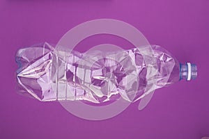 Crashed plastic bottle on blue purple background. Plastic utilisation concept. Ecological problem, global environment.