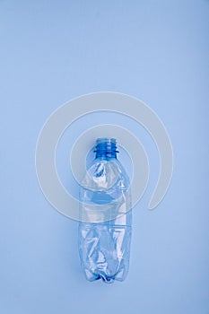 Crashed plastic bottle on bright blue background. Plastic utilisation concept. Ecological problem, global environment.