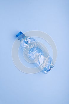 Crashed plastic bottle on bright blue background. Plastic utilisation concept. Ecological problem, global environment.