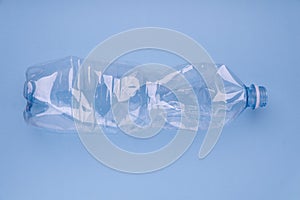 Crashed plastic bottle on bright blue background. Plastic utilisation concept. Ecological problem, global environment.