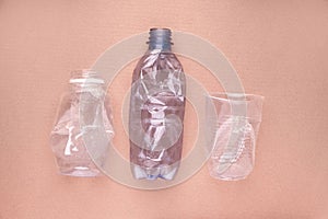 Crashed plastic bottles and a cup on beige tan background. Plastic utilisation concept. Ecological problem, global