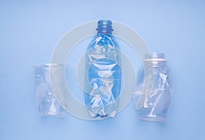 Crashed plastic bottles and a cup on bright blue background. Plastic utilisation concept. Ecological problem, global