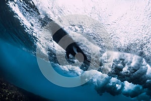 Crashing wave with foam and air bubbles and surfboard underwater. Transparent sea water