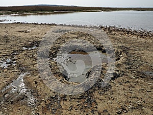 Crater with gray volcanic healing clay. A hole with a prominent amorphous mass from the depths of the earth. Mud and gas