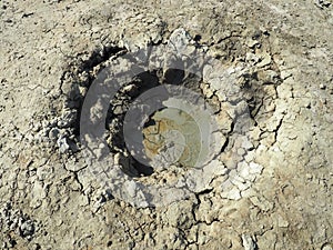 Crater with gray volcanic healing clay. A hole with a prominent amorphous mass from the depths of the earth. Mud and gas eruption