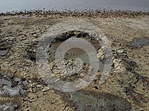 Crater with gray volcanic healing clay. A hole with a prominent amorphous mass from the depths of the earth. Mud and gas eruption