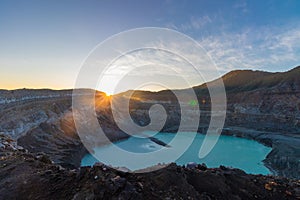 Crater of the Poas volcano at sunrise surrounded by volcanic rocks in the Poas Volcano National Park in the Alajuela province of