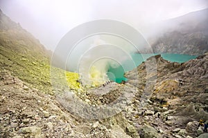 Crater of a volcano with a green sulfuric volcanic lake and volcanic smoke. View of the smoking volcano Kawah Ijen in Indonesia. M