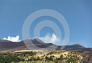 Etna crater and green forest landscape between lava flows and blue sky; Holidays and adventures photo