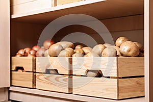 Crates with potatoes and onions on shelf