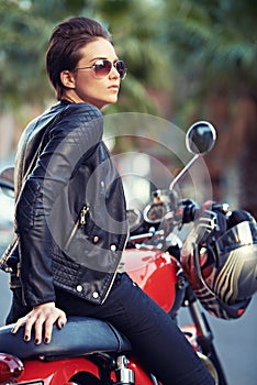 Craving the open road. A gorgeous biker in leathers sitting atop her awesome motorbike.