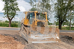 Crawler bulldozer clears the ground with a metal shield. Landscaping.