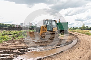Crawler bulldozer clears the ground with a metal shield. Landscaping. Road construction works