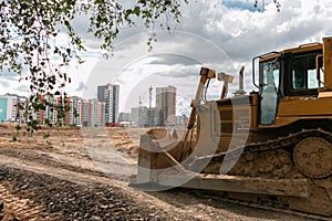 Crawler bulldozer clears the ground with a metal shield. Road construction works. Landscaping.