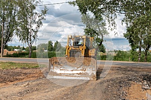 Crawler bulldozer clears the ground with a metal shield. Road construction works. Landscaping. Construction works