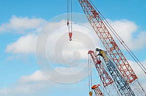 Crawler crane against blue sky and white clouds. Real estate industry. Red crawler crane use reel lift up equipment in