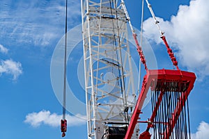 Crawler crane against blue sky and white clouds. Real estate industry. Red-white crane use reel lift up equipment in construction