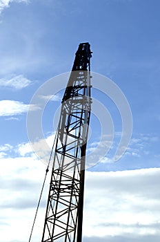 Crawler crane standing tall silhouette with blue sky background