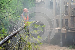 The crawler drilling rig drills well, there is a lot of dust when drilling a well. Drilling of exploration wells in the forest